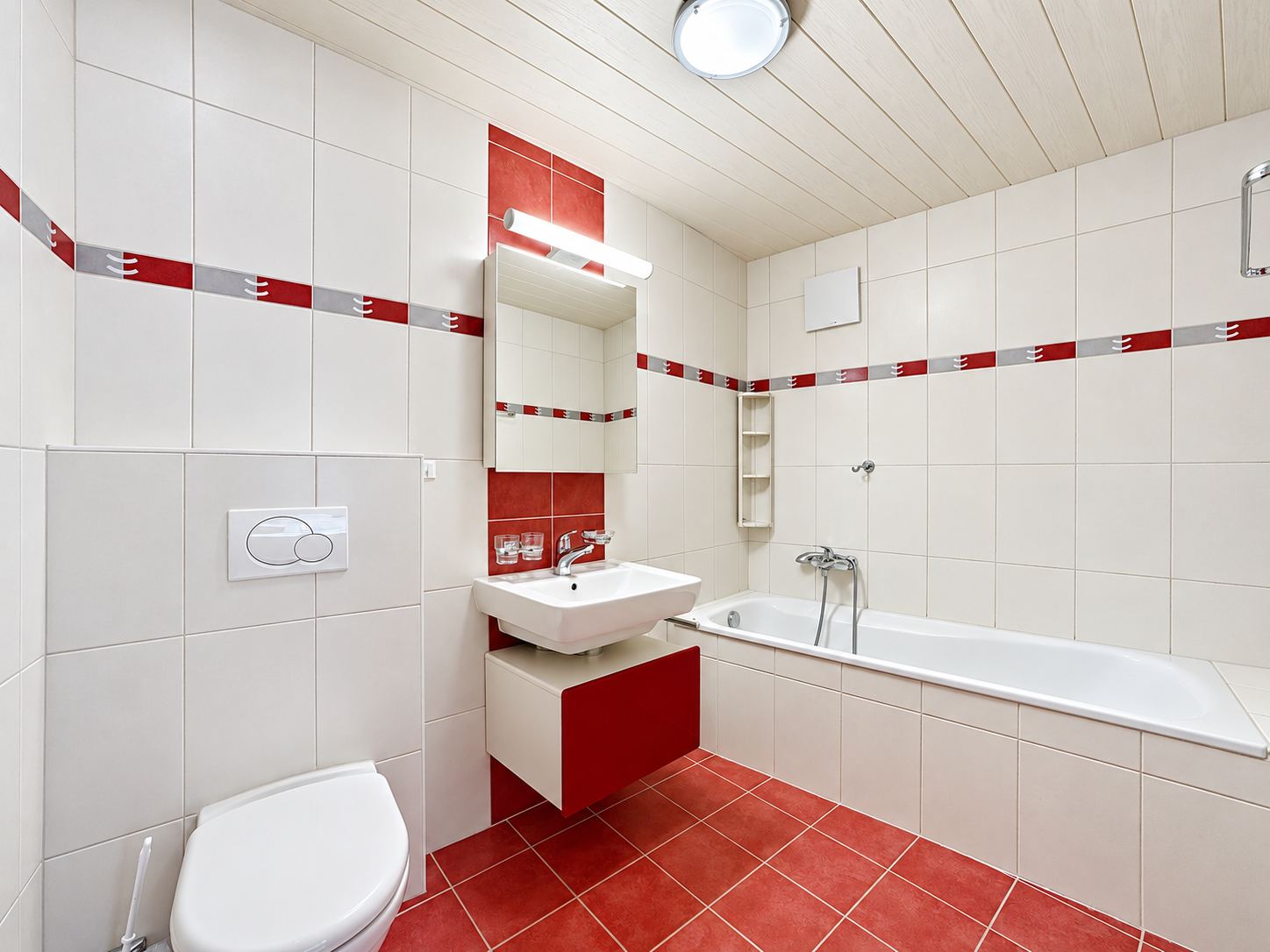 La salle de bain avec baignoire, meuble vasque et WC.
