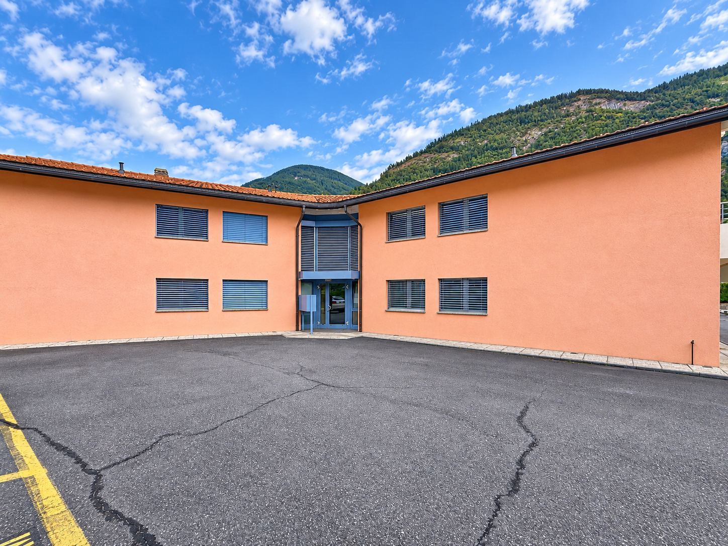 L'entrée de l'immeuble depuis la cour, avec le coteau en arrière-plan.