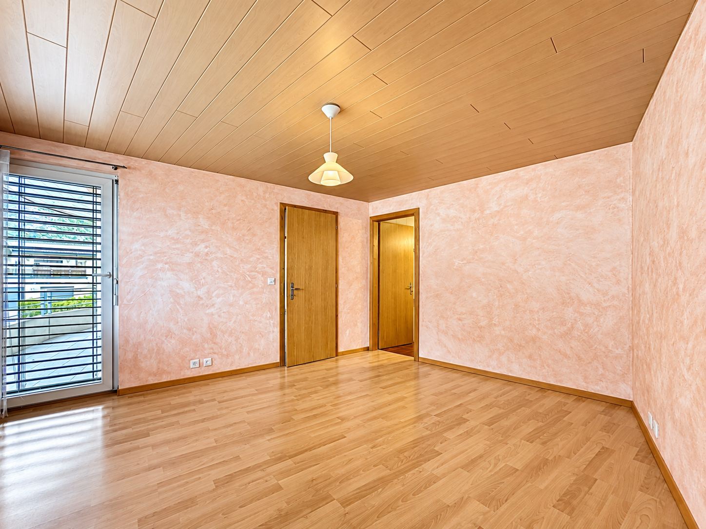 La chambre parentale au niveau inférieur, avec porte-fenêtre et stores.